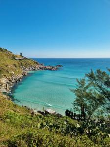 a view of a beach on a hill with the ocean at Casa e Kitnet - Praia Grande Centro in Arraial do Cabo +19 photos