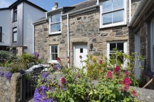 een stenen huis met bloemen ervoor bij Piskey Cottage, Mousehole - Close to Harbourside - Free WiFi - Free Parking in Mousehole