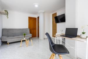 a living room with a chair and a desk with a laptop at Parque de Envigado a 350 mts, 2bd, 500mb internet in Envigado