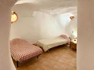 een kamer met 2 bedden en een tafel in een kamer bij Cortijo Maya, maison troglodyte pour 10 personnes in Alhama de Almería +18 foto's