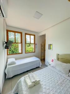 a bedroom with two beds and two windows at Tô em Casa in Lençóis
