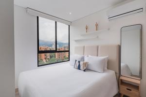 a white bedroom with a large bed and a window at Grand By Jalo in Medellín +76 photos