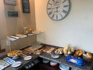 a buffet with a large clock and a bunch of pastries at Pousada Dom Diego in Jacaraípe