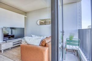 a living room with a couch and a tv on a balcony at Urban Oasis at One Rosebank in Johannesburg