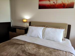 a bed with white pillows and a painting on the wall at Romantic Hillside Escape Sea View in Budva