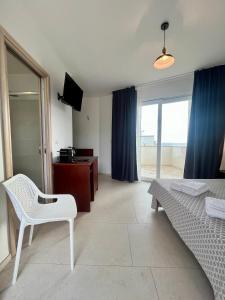 una camera con letto, sedia e televisore di Rooms del Moro a Patù