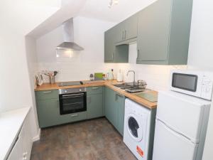 a kitchen with green cabinets and a washer and dryer at Medical Hall in Cemaes Bay