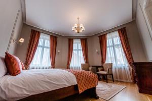 a bedroom with a bed with a chandelier and windows at Casa Petra in Sibiu