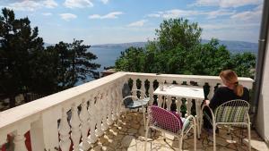a woman sitting at a table on a balcony at Apartments Škrobot in Senj