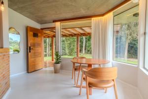 a dining room with a table and chairs and windows at Vila da toca in Ibitirama
