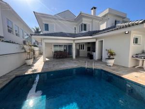 a house with a swimming pool in front of a house at Casa Condomínio Fechado Hanga Roa Bertioga in Bertioga