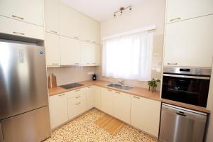 Una cocina con gabinetes blancos y un refrigerador de acero inoxidable. en Casa Lamacchia by CorfuEscapes, en Corfú