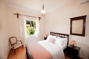 Un dormitorio con una cama y una silla y una ventana. en Casa Lamacchia by CorfuEscapes, en Corfú
