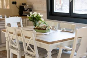 a table with white chairs and a vase of flowers on it at Ozónia Wellnes House in Šahy