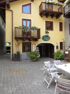 a yellow building with a patio with tables and chairs at Affittacamere Al Cantoun in Chiomonte