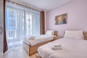 two beds in a room with a window at New! Modern Studio in central Malta by SF Homes in Msida