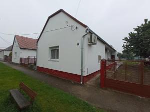 ein weißes Haus mit einem roten Zaun in einem Garten in der Unterkunft Pyramids Piramis Vendeghaz in Magyarbóly