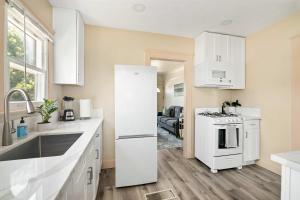 a kitchen with white cabinets and a white refrigerator at Cozy Ocean Beach Bungalow in San Diego