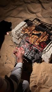 a person is cooking food on a grill at Shasha Ecolodge in Siwa +41 photos