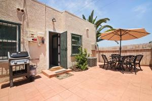a patio with a grill and tables and an umbrella at Cozy Ocean Beach Bungalow in San Diego