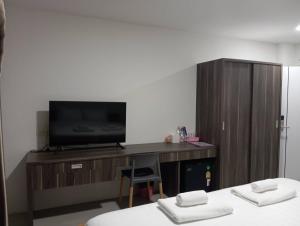 a room with two beds and a tv and a desk at VS Place in Nonthaburi