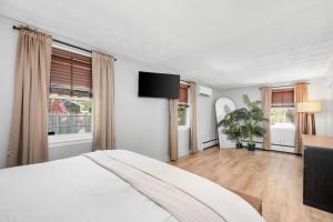 a white bedroom with a bed and a flat screen tv at 7 Raymond Avenue South Yarmouth -The Sandlot Shanty in South Yarmouth