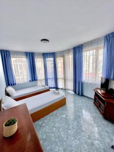 a bedroom with a large bed and blue curtains at Vila Victoria Primorsko in Primorsko