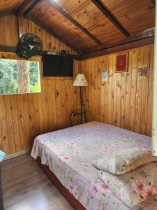 ein Schlafzimmer mit einem Bett in einem Holzzimmer in der Unterkunft Cabana Hostel nas Árvores EcoPark in São Pedro
