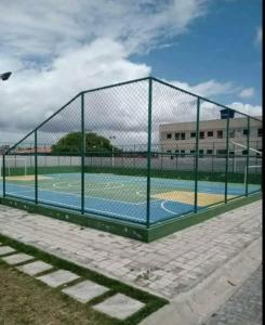 Una valla alrededor de una cancha de baloncesto en un edificio. en Apart no condomínio Residencial Ipojuca, en Caruaru