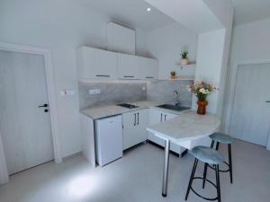 a white kitchen with a sink and a table at mesogios enjoyable living in Kallithea Halkidikis