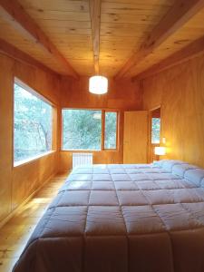 a large bed in a room with two windows at Cabaña Nido del Bosque in San Carlos de Bariloche