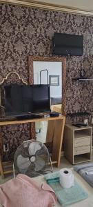 a living room with a tv and a desk with a fan at Studio Centro Floripa 05 in Florianópolis