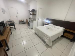 a bedroom with a bed and a table and a kitchen at Condo ipanema 209 in Rio de Janeiro