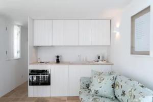 a kitchen with white cabinets and a couch in a room at Segredos da Muralha in Óbidos