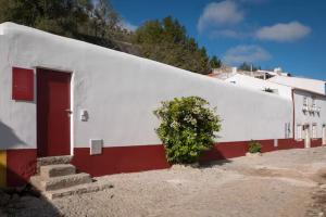 a large white building with a door and a bush at Segredos da Muralha in Óbidos
