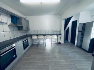 une cuisine avec des armoires blanches et une table et des chaises dans l'établissement The Cozy Stay House, à Langley Mill