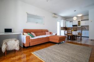 a living room with a brown couch and a kitchen at Apartmani Ljubljeni in Primošten