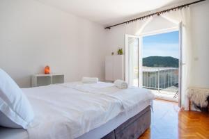 a white bedroom with a large bed and a large window at Apartmani Ljubljeni in Primošten