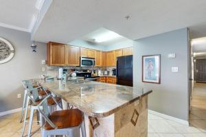a kitchen with a large island with bar stools at Pelican Beach Resort 504 in Destin