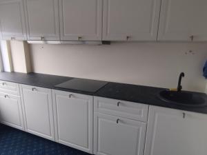 a kitchen counter with a sink and white cabinets at Via Baltica Panevezys Self Check-in Hotel in Panevėžys