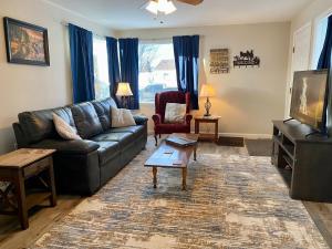 a living room with a leather couch and a tv at Bo's Copper City Charmer, easy Freeway Access, open floorplan in Butte