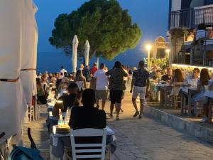 a crowd of people walking down a sidewalk with tables and chairs at Villa Evita , penthouse, 53m2 ,Athytos , astonishing sea view in Afitos