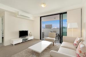 a living room with a couch and a tv at Republic Apartments Brisbane City in Brisbane