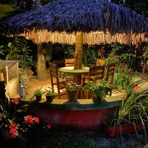 a patio with a table and chairs and a straw umbrella at Pousada Cantinho do Dodó in Mulungu