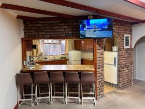a kitchen with a bar with a tv on a brick wall at M&D Guest House in Bellville