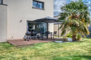 a patio with a grill and a table with an umbrella at L'Océane Maison avec jardin in Vannes