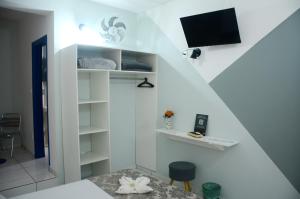 a white room with a bed and a tv on a wall at Metro Hotel in Águas de Lindóia