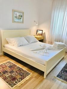 Una cama blanca en un dormitorio con una mesa. en Cosy and Comfy Apartment 2 min walk to the beach, en Sarandë