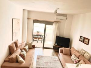 Una sala de estar con un sofá y un televisor. en Cosy and Comfy Apartment 2 min walk to the beach, en Sarandë