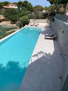 a swimming pool next to a stone wall with a swimming pool at Vasiliki's Villa Beach Front and Pool in Porto Heli